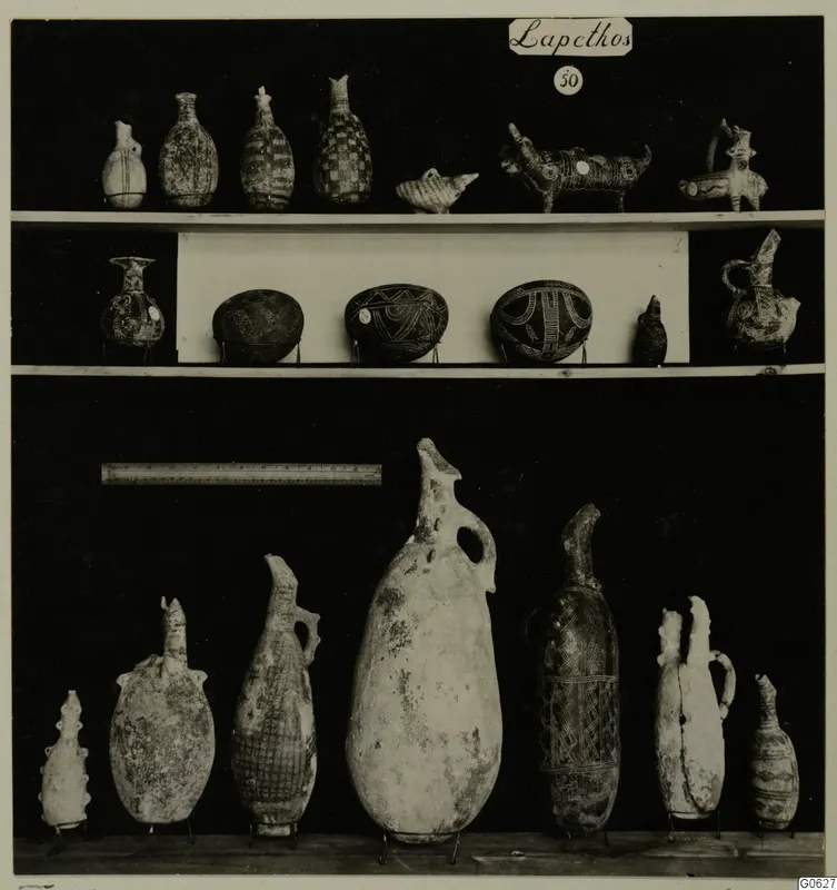 Pottery jugs, juglets and bowls from Lapithos Markides T.50, arranged on three shelves against a black background