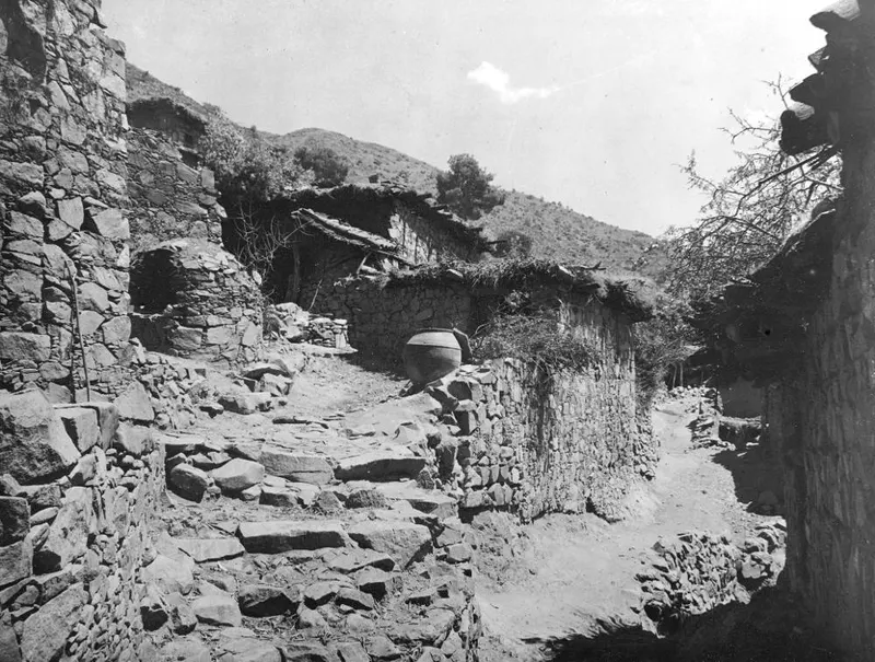 Stone-walled village lane with a stepped path and a large earthenware jar on a low wall