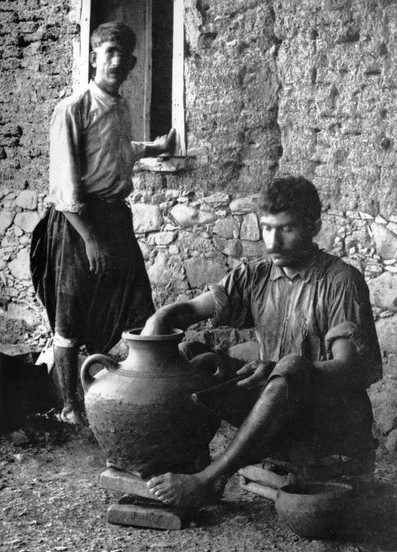 Man turning a large clay vessel at Klirou farmstead F, with a second man standing at a window behind him