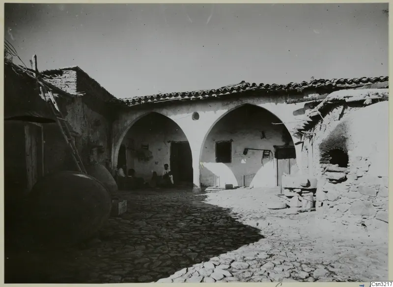Cobbled courtyard at Klirou with two arched openings, a leaning ladder and large jars