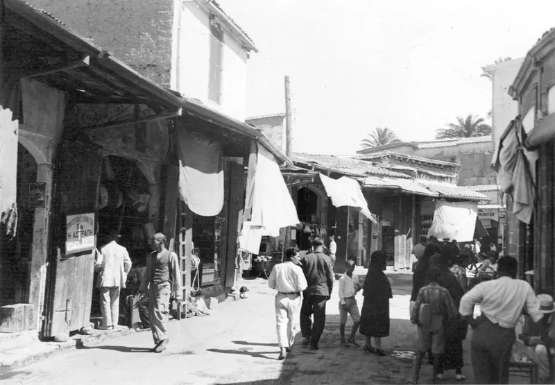 Street in Nicosia lined with shopfronts and hanging white cloths, with people walking along it