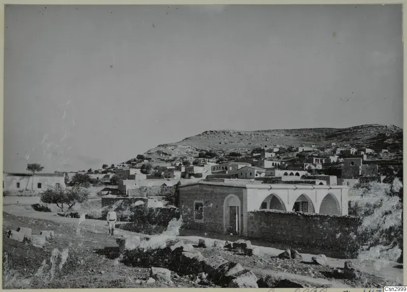 Village of flat-roofed stone houses on a rocky hillside on the Karpas peninsula, with one man walking on a path