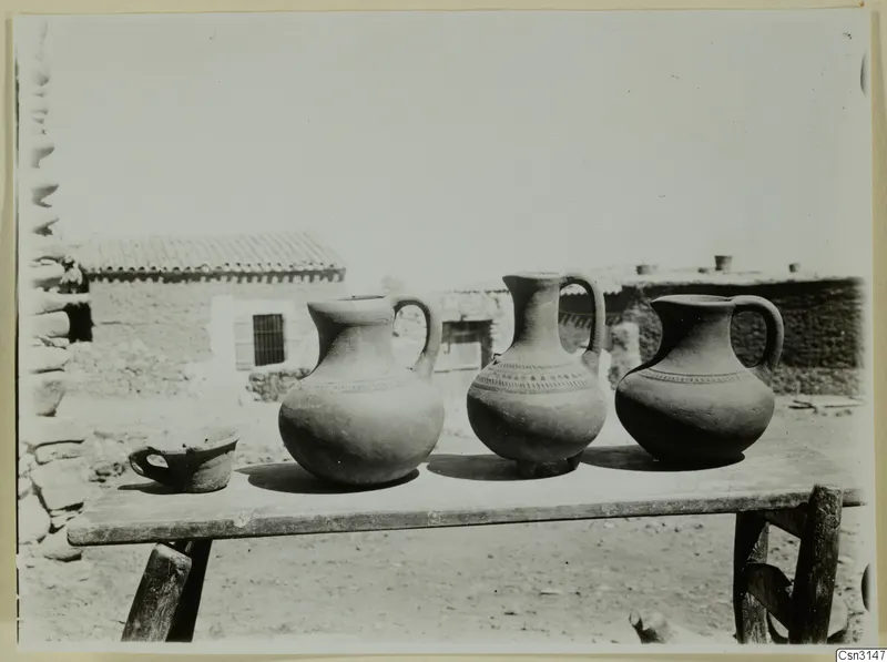 Three modern water jars and a small cup on a wooden table at farmstead A, Klirou