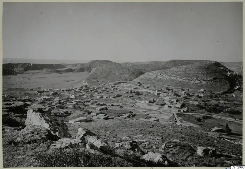 Village of low buildings spread across a valley at Galinoporni, Karpas peninsula, seen from rocky high ground.