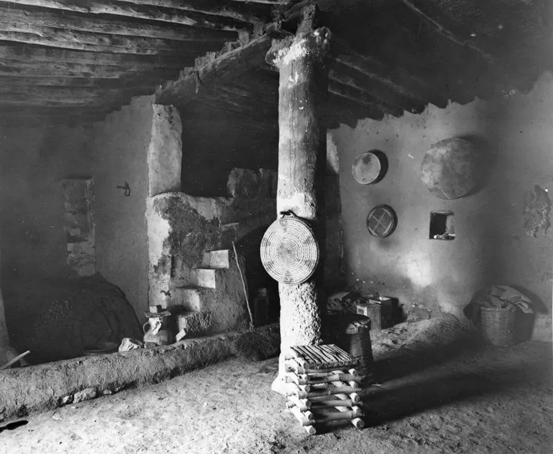 Interior of a traditional house with a timber pillar, mud-plastered walls and a stepped mud structure