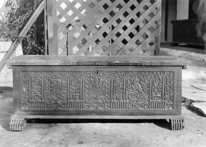 Carved wooden clothes chest, so-called sendudzin, standing outdoors in front of a lattice fence
