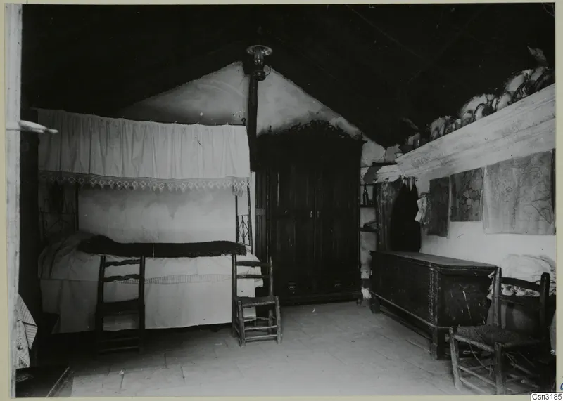 Interior of a room at Lazania with a canopied bed, wooden chairs, a dark cupboard and a chest