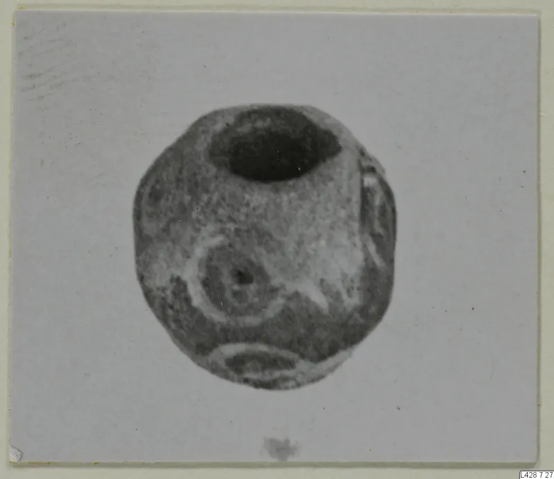 Rounded stone object with a wide opening at the top and a ring-shaped motif on its face