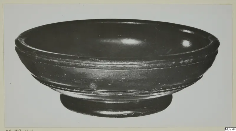 Black-glazed pottery bowl with a low ring foot and two grooves on the outer wall.