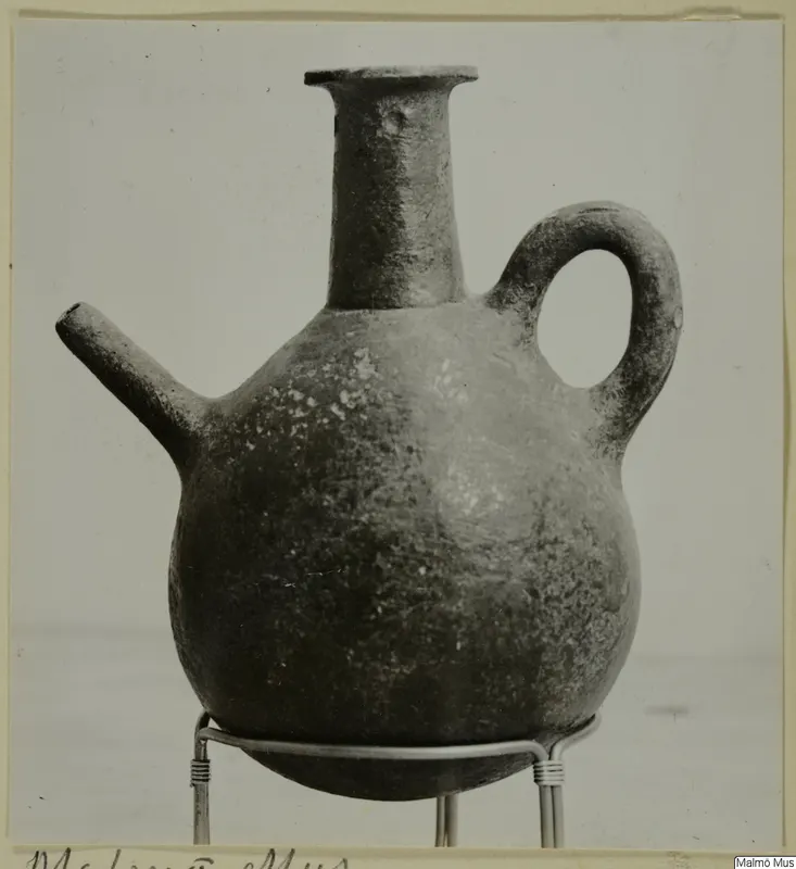 Red Polished III jug with a side spout and loop handle, standing on a wire stand
