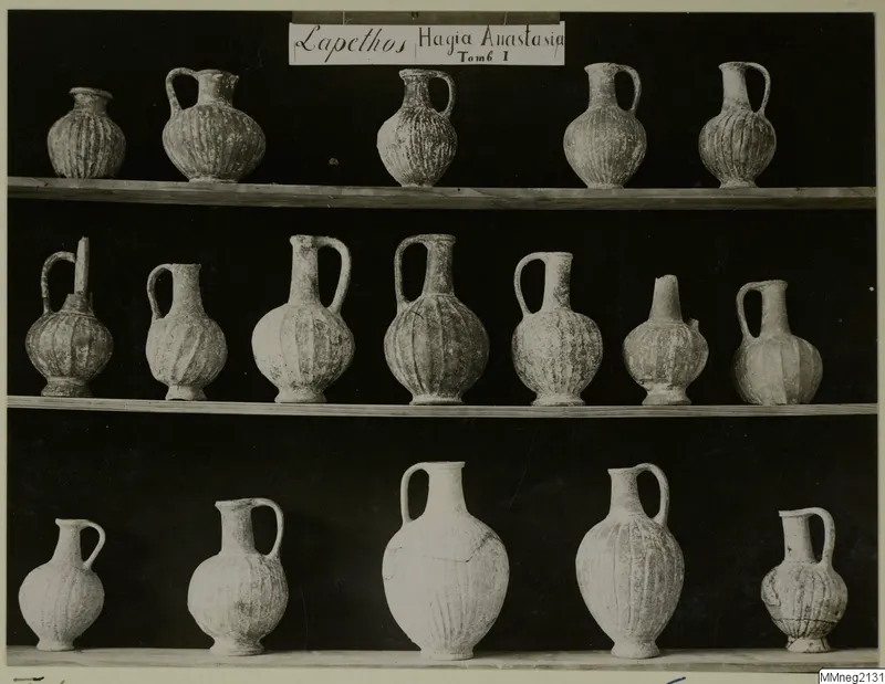 Three shelves of ribbed pottery jugs with single handles, Lapithos Markides T.1, photographed against a black background