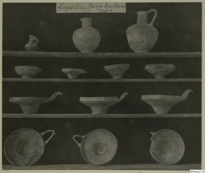 Jugs and bowls from Lapithos Markides, T.1, arranged on four shelves against a dark background