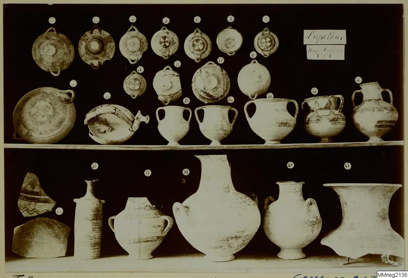 Shelved group of numbered pottery vessels from Lapithos Markides Tomb 2, including bowls, jugs and large jars.