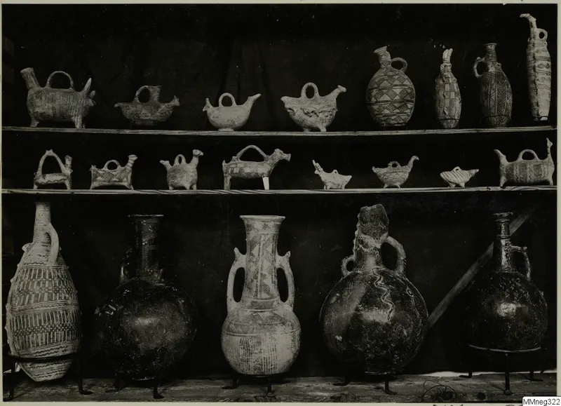 Pottery vessels on three shelves: small animal-shaped and bottle-shaped jugs above, large jars on metal stands below.