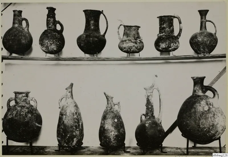 Eleven pottery jugs and jars from Cyprus, shown in two rows at the Cyprus Museum