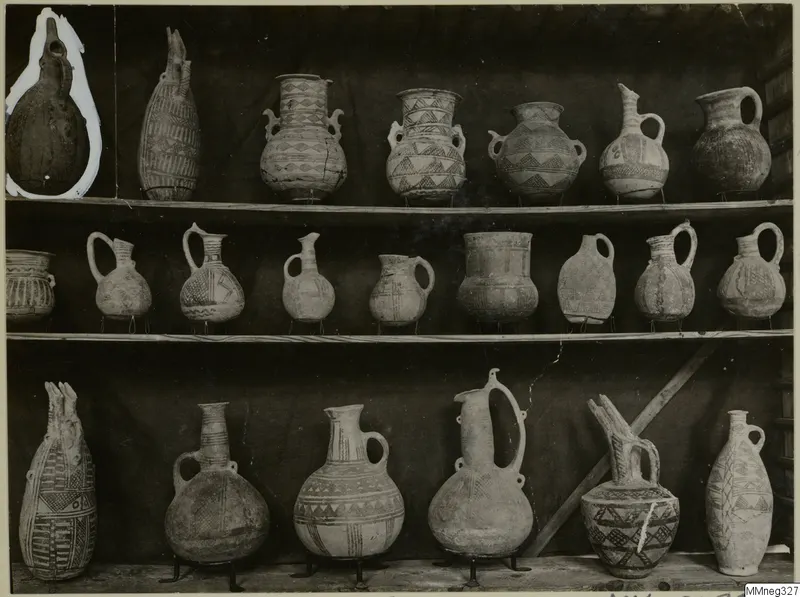 Three shelves of painted pottery jugs and jars, pattern-decorated, shown against a dark cloth at the Cyprus Museum.