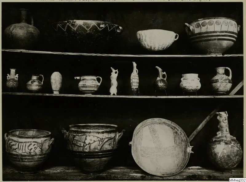Three shelves of ancient pottery vessels and small figures from Cyprus, shown in the Cyprus Museum, with painted bands, zigzags and spirals.