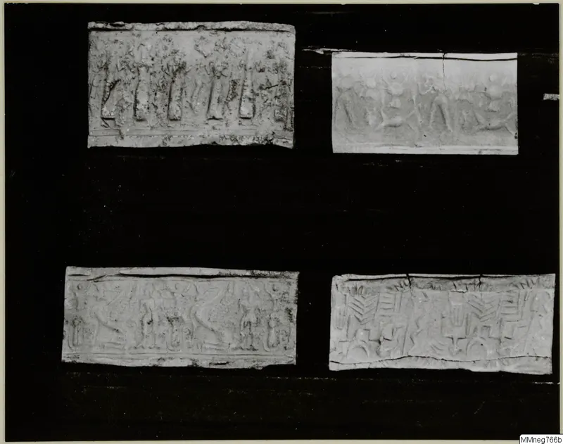 Four rectangular pieces, each with raised figures and patterns carved in horizontal bands, set on a black backing