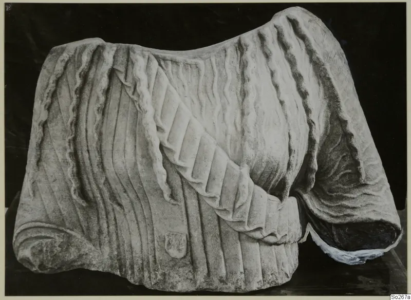 Carved marble sculpture fragment with deep drapery folds and a broken edge at the right end