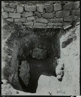 Excavated tomb at Lapithos, Vrysi tou Barba, with a dry-stone wall at the back and large stones inside the cut