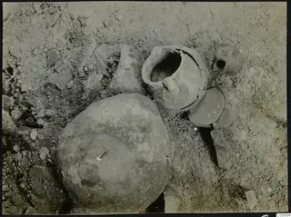 Pottery vessels and sherds lying in sandy soil during excavation of Tomb 302 at Lapithos