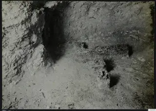 Tomb 302 at Vrysi tou Barba, Lapithos: chamber interior with a ledge holding scattered bone fragments and stones.