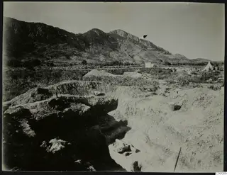 Excavation trenches at Lapithos with a white tent and a mountain ridge behind