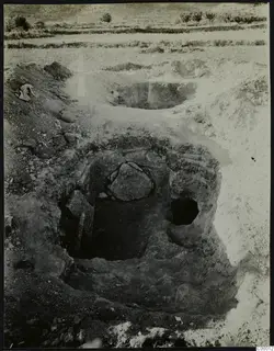 Tomb 315 at Lapithos during excavation, with a large stone lying inside the open tomb chamber and spoil heaps around it