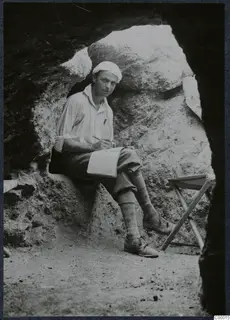 Erik Sjöqvist sitting in Tomb 306 at Lapithos, writing in a notebook with a pencil.
