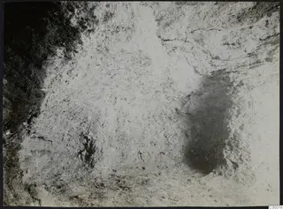 Interior of Tomb 302 at Vrysi tou Barba, Lapithos, during excavation, showing a rough pale surface and shadowed hollows.