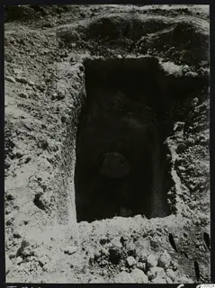 Tomb 308 at Lapithos, Vrysi tou Barba, during excavation, showing a rectangular tomb opening cut into the soil with a stone inside.