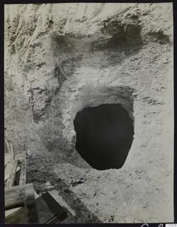 Tomb 302 at Lapithos, Vrysi tou Barba, during excavation, showing a dark tomb opening cut into a pale earth face.