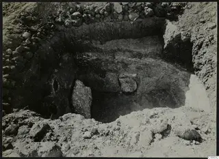 Tomb 311 at Lapithos, Vrysi Tou Barba, during excavation, showing an upright stone slab and stones in the chamber