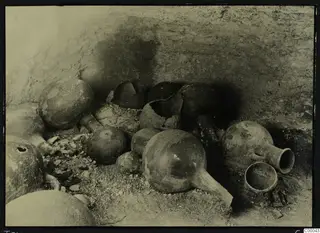 Pottery vessels in situ on the floor of Lapithos Tomb 303A, against a rough tomb wall