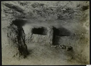 Tomb 313 A at Lapithos, Vrysi tou Barba: rock-cut tomb chamber with standing rock pillars and loose stones on the floor.