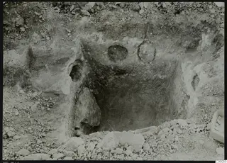 Rock-cut tomb chamber 316 at Vrysi tou Barba, Lapithos, during excavation, with stones and a box