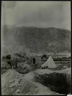 Excavation at Lapithos with a white tent, a small wooden hut and a donkey beside a stone wall, with mountains behind.