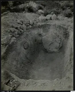 Tomb 320 at Vrysi tou Barba, Lapithos, during excavation, showing the cut chamber with a large stone and a box of stones
