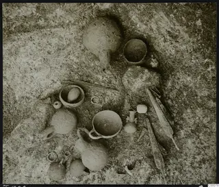 Tomb 320 at Lapithos: pottery vessels and small objects lying on the tomb chamber floor during excavation.