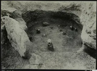 Tomb 323 at Lapithos, Vrysi tou Barba, during excavation, with pottery vessels scattered on the chamber floor.