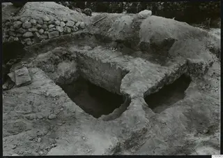 Tomb 405 at Lapithos Kastros during excavation, showing two rectangular openings cut into the ground with spoil heaps around them