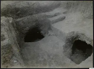 Two excavated tomb openings in an earth cutting at Vrysi tou Barba, Lapithos, with a stepped cut above them