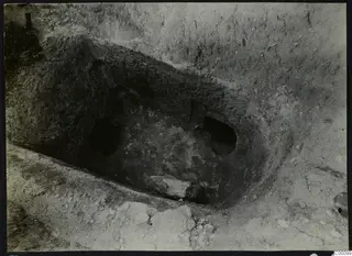 Tomb 312 at Lapithos, Vrysi tou Barba, during excavation, showing the open tomb chamber with a large stone inside.