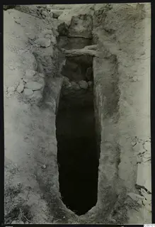 Tomb 410 at Lapithos Kastros during excavation: a narrow cut descending between earth banks, with timber beams and stones