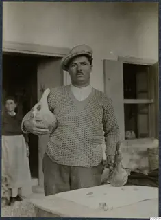 Man in a cap holding two pottery vessels, one in each hand, with a woman in a doorway behind him.