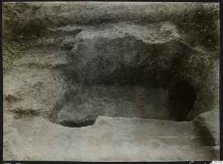 Excavated tomb at Vrysi tou Barba, Lapithos, with a dark opening in the cut rock face during excavation