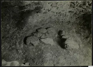 Tomb 301 at Lapithos during excavation, showing stones lying on the sandy floor of the tomb chamber.
