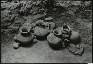 Tomb chamber at Lapithos with a group of clay vessels set against the earth wall.