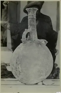 Red Polished II jug with a long neck, ring bands and one strap handle, in front of a man in a cap