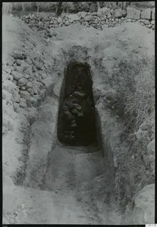 Tomb 409 at Lapithos during excavation: a sloping passage leads down to a dark tomb chamber filled with stones